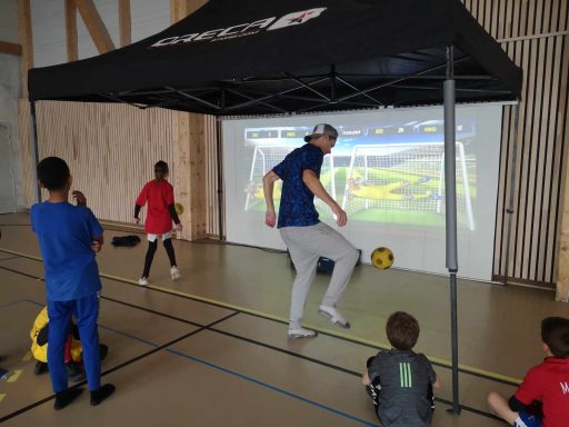 Entraînement au football avec un écran projetant un jeu interactif, enfants en action.