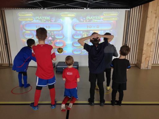 Des enfants jouant à un jeu interactif projeté sur un mur.